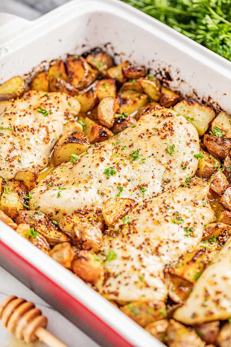 Honey dijon chicken and potatoes in a baking dish.