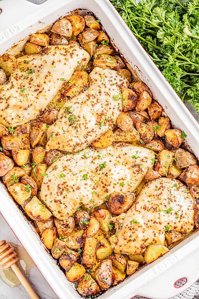 Overhead view of baked honey dijon chicken and potatoes in a baking dish.