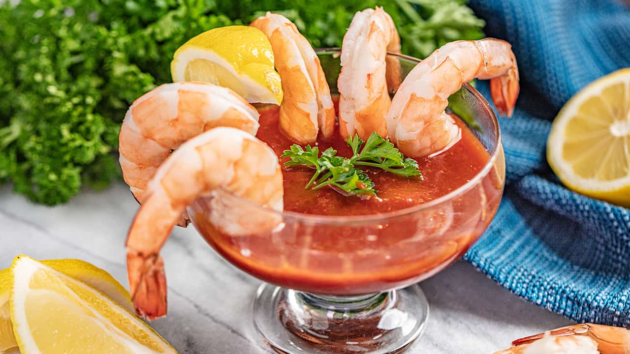 Shrimp hanging over the edge of a cocktail glass.