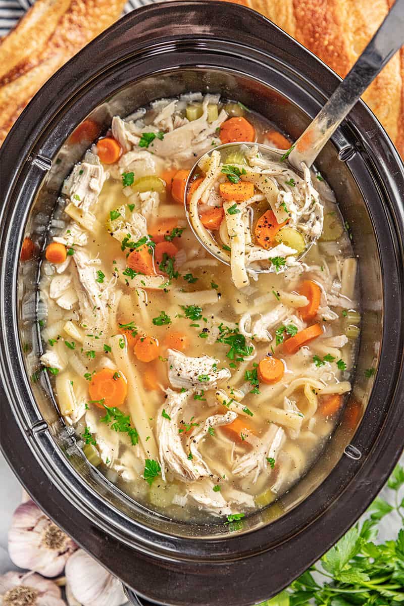 Overhead view of a crockpot filled with chicken noodle soup.