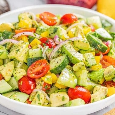 A white serving bowl filled with tomato and avocado salad.