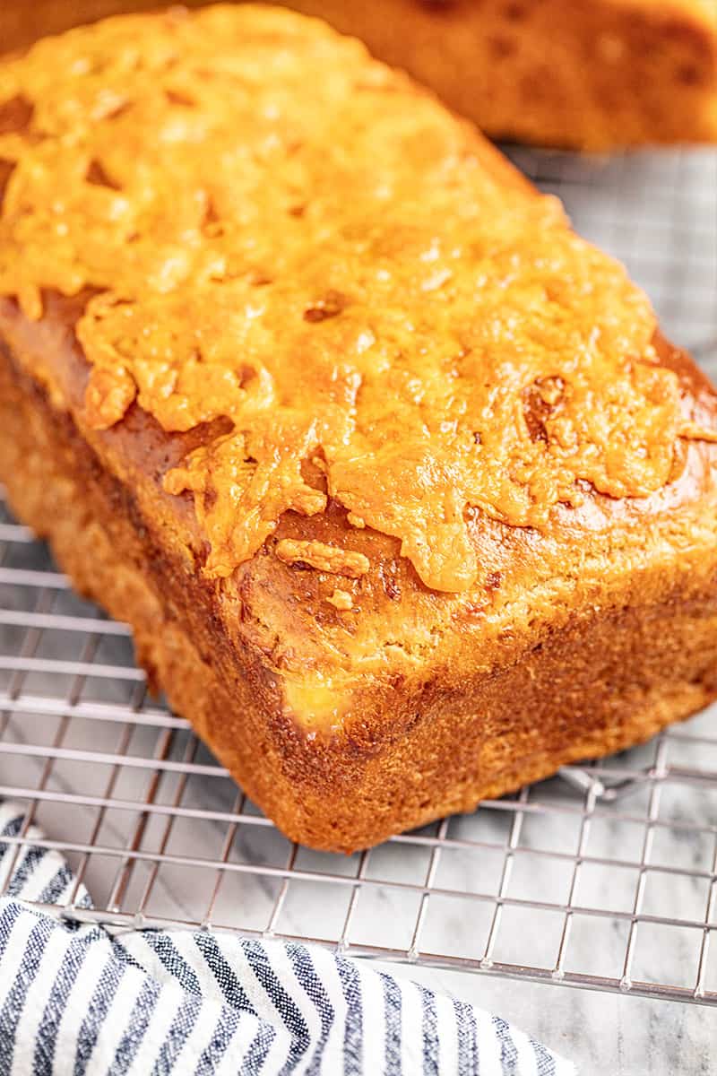 A loaf of cheddar batter bread on a cooling rack.