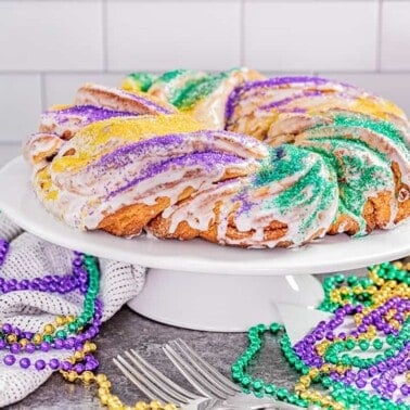 A traditional king cake on a cake stand.