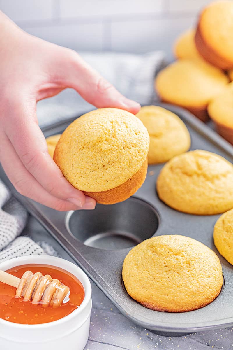 A person holding a cornbread muffin.