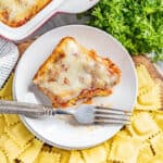 Overhead view of a piece of ravioli lasagna on a plate with a bite removed.