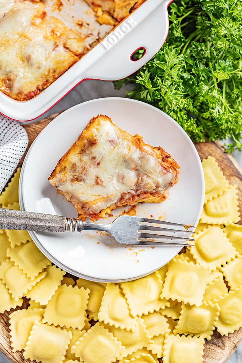 Overhead view of a piece of ravioli lasagna on a plate with a bite removed.