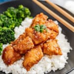 General Tso Chicken pieces with sesame seeds served over a bed of white rice.