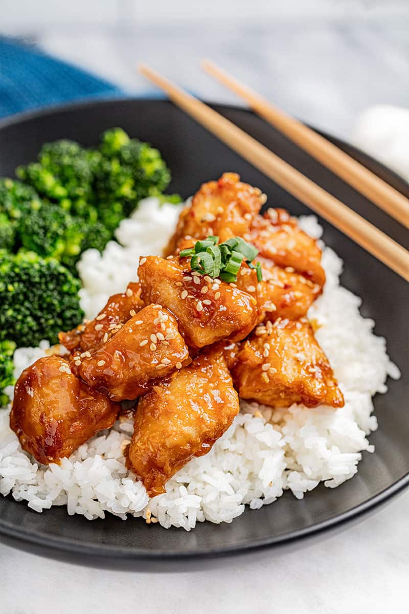 General Tso Chicken pieces with sesame seeds served over a bed of white rice.