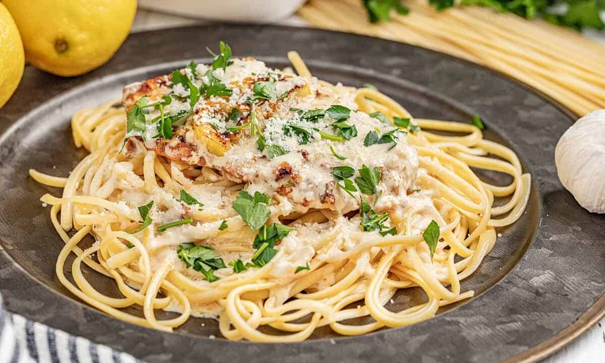 Chicken francese with spaghetti noodles on a dinner plate.