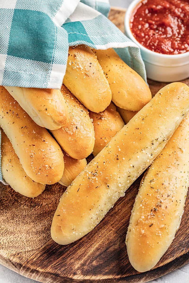 Homemade breadsticks on a wooden plate.