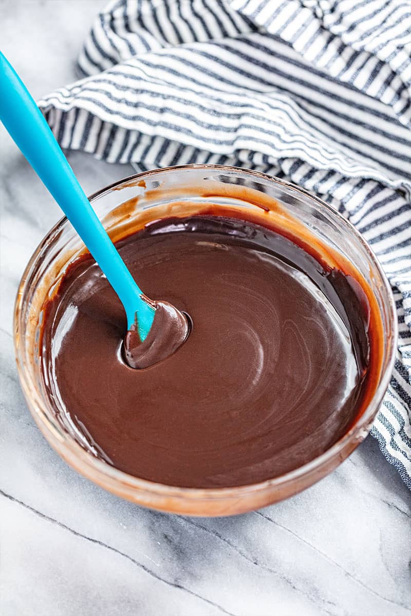 A bowl of chocolate ganache with a spatula resting in it.