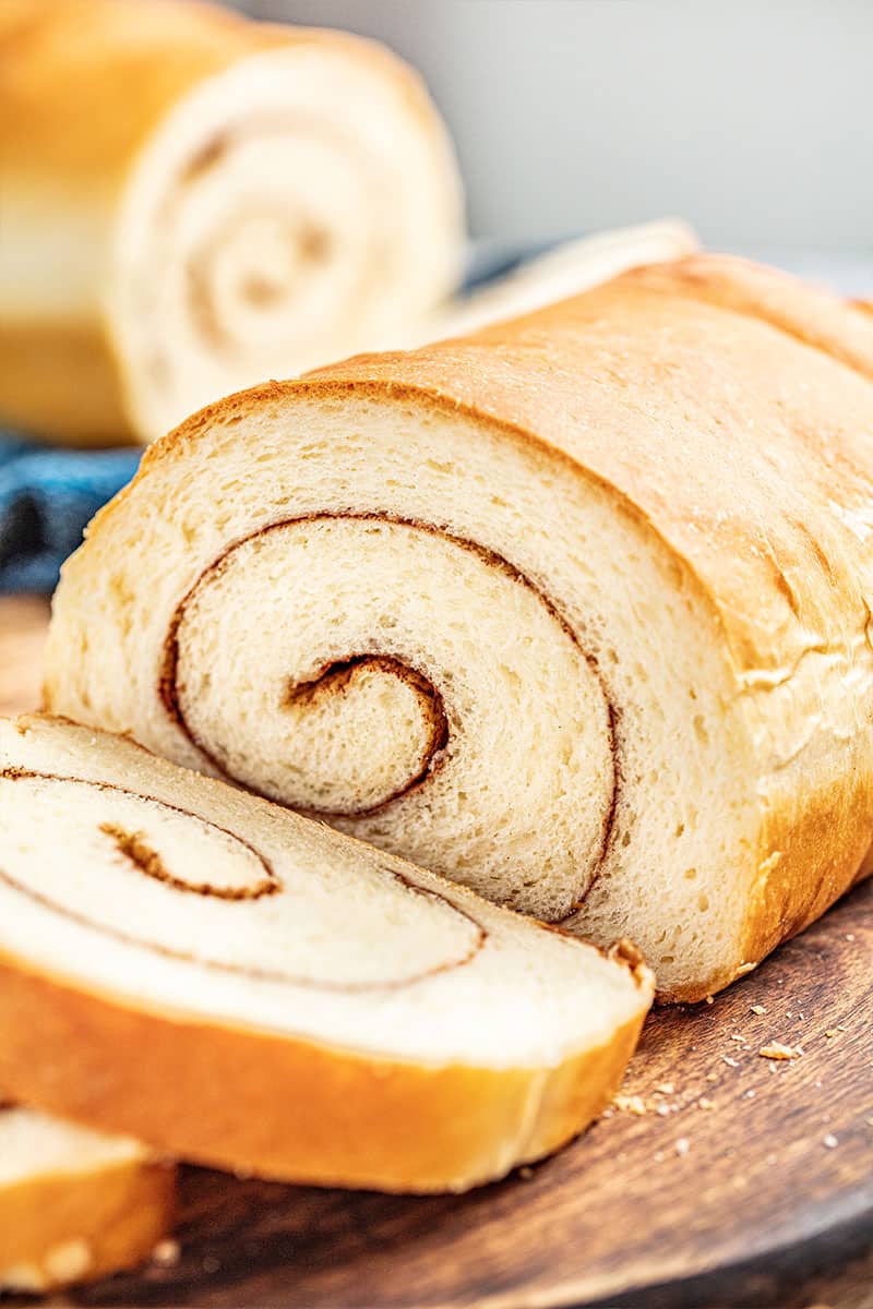 A loaf of cinnamon swirl bread with a slice cut off.