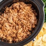 Overhead view of honey chipotle pulled pork in a slow cooker.