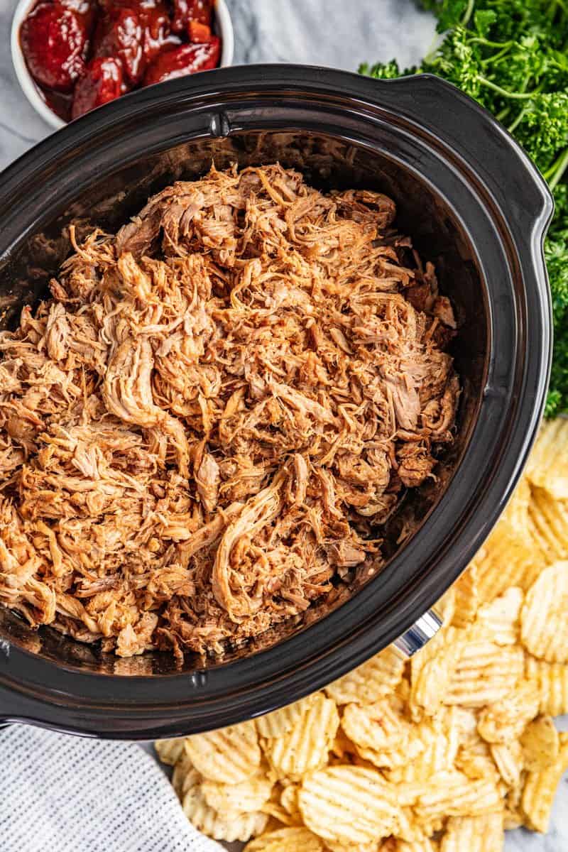 Overhead view of honey chipotle pulled pork in a slow cooker.