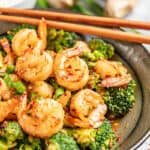 Spicy szechuan shrimp and broccoli with chopsticks.