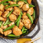 Overhead view of a skillet filled with sticky honey garlic chicken and snap peas.