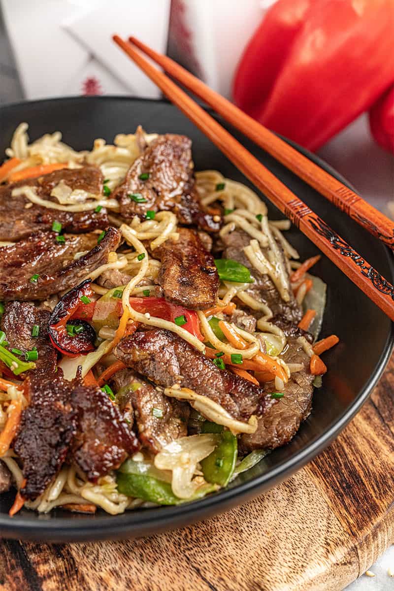 Close up view of beef lo mein with chopsticks.