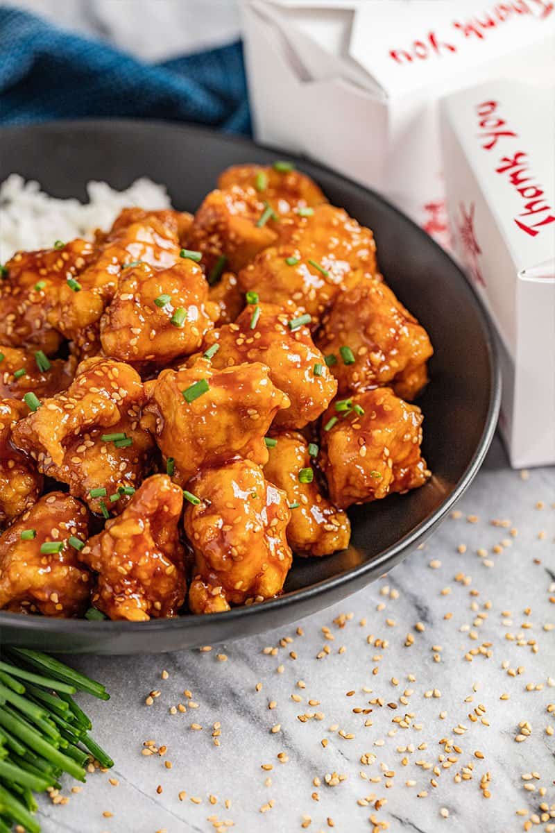 A bowl filled with crispy and sweet sesame chicken and rice.