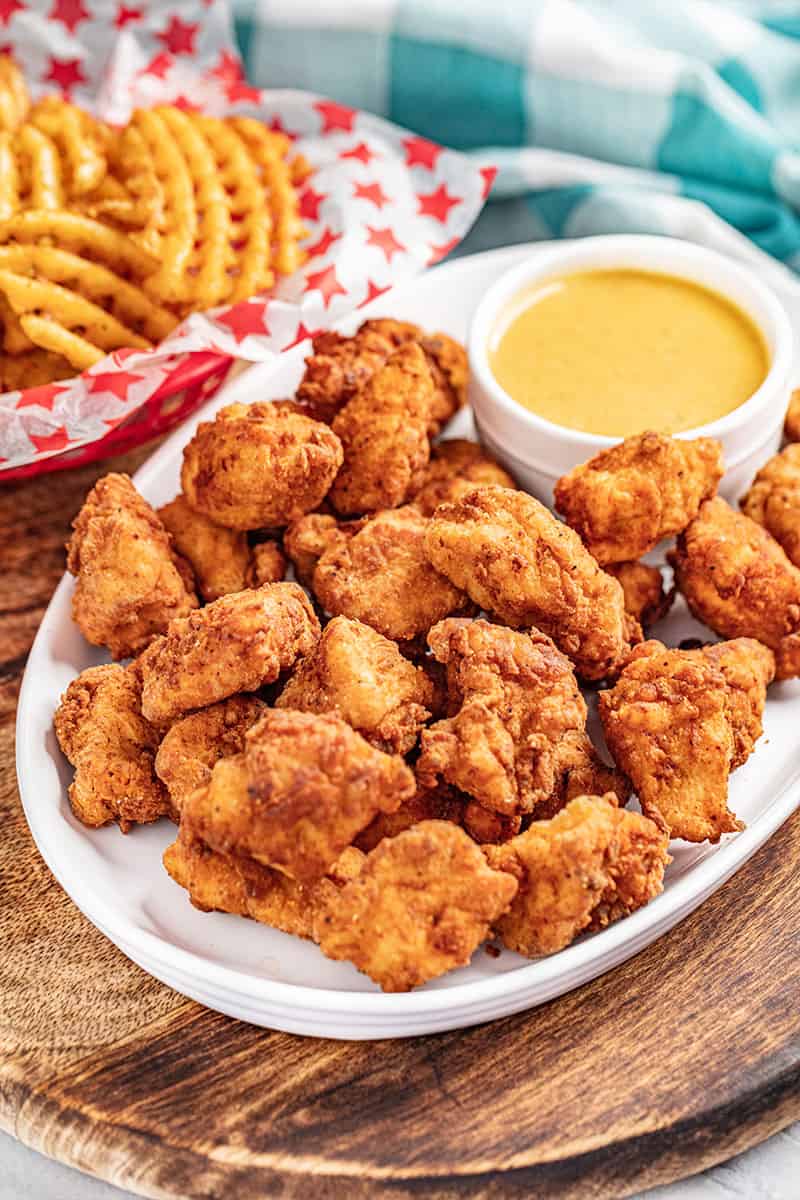 Copycat Chick Fil-A nuggets with dipping sauce on a serving platter with waffle fries on the side.