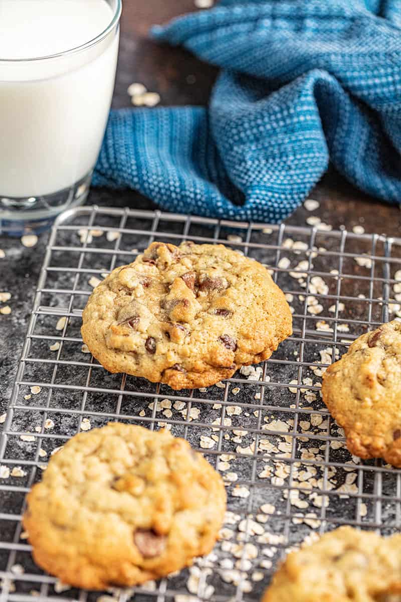 Oatmeal chocolate chip cookies on a wire rack with a glass of milk.