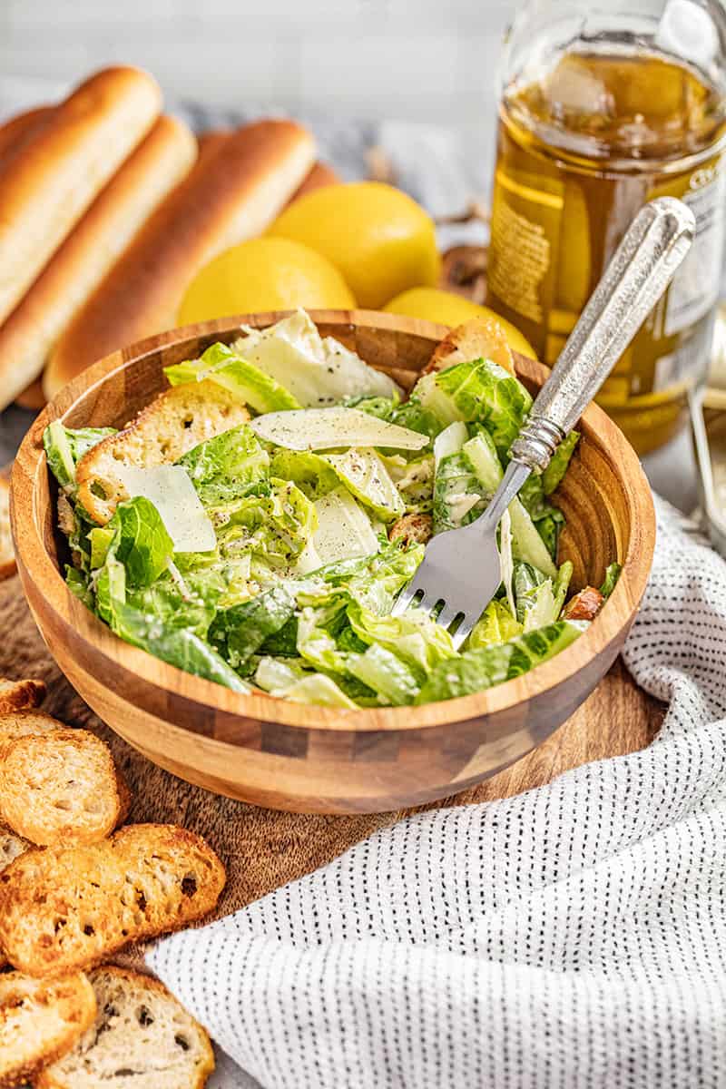 A wooden salad bowl filled with a Caesar salad.