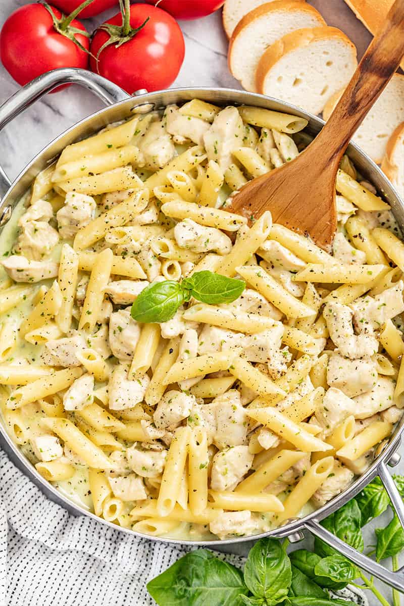 Overhead view of a stainless steel pot filled with chicken pesto noodles.