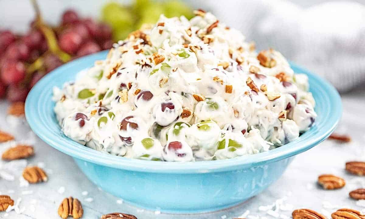 A full bowl of creamy grape salad with pecans and coconut.
