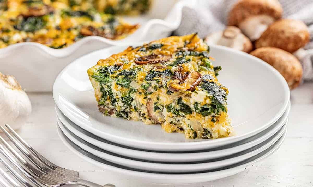 A piece of crustless spinach quiche on a stack of plates.