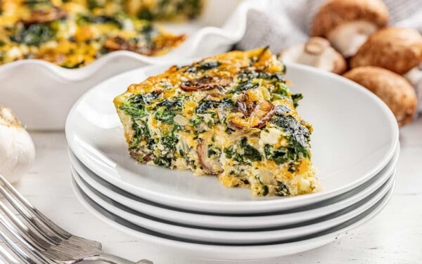A piece of crustless spinach quiche on a stack of plates.