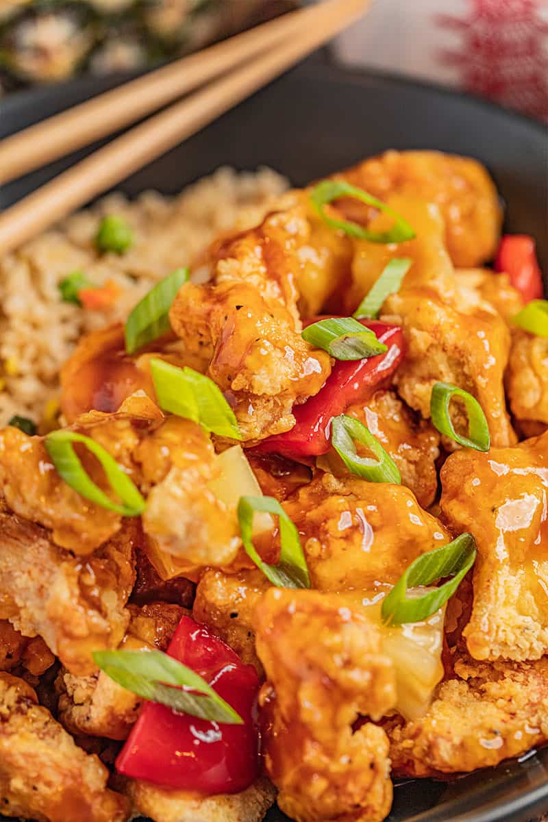 Close up of sweet and sour chicken with sliced ​​green onion on top.