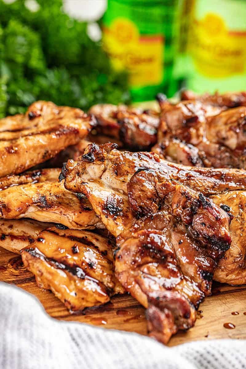 Juicy grilled chicken breast and thighs on a wood cutting board.