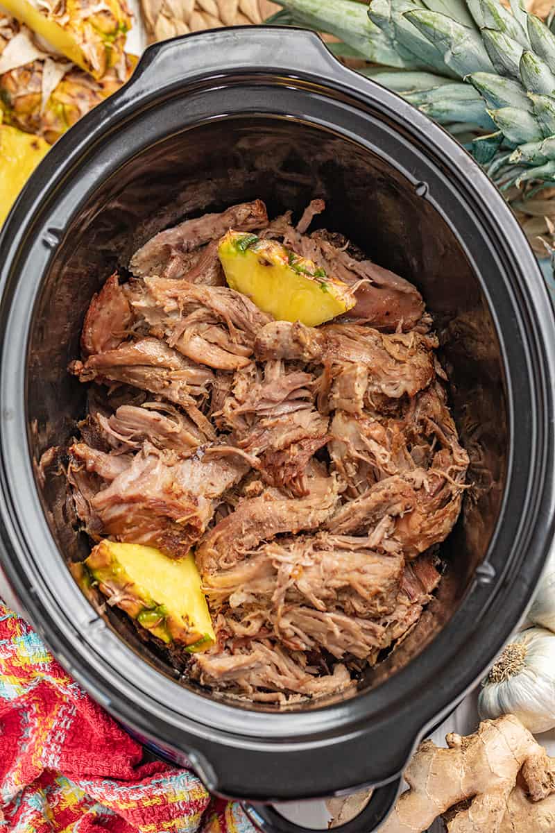 Overhead view inside of a slow cooker filled with kalua pork and pineapple.