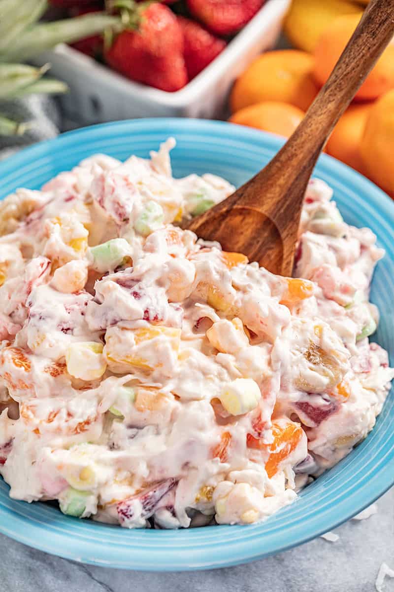 Ambrosia salad with a wooden spoon in the bowl.