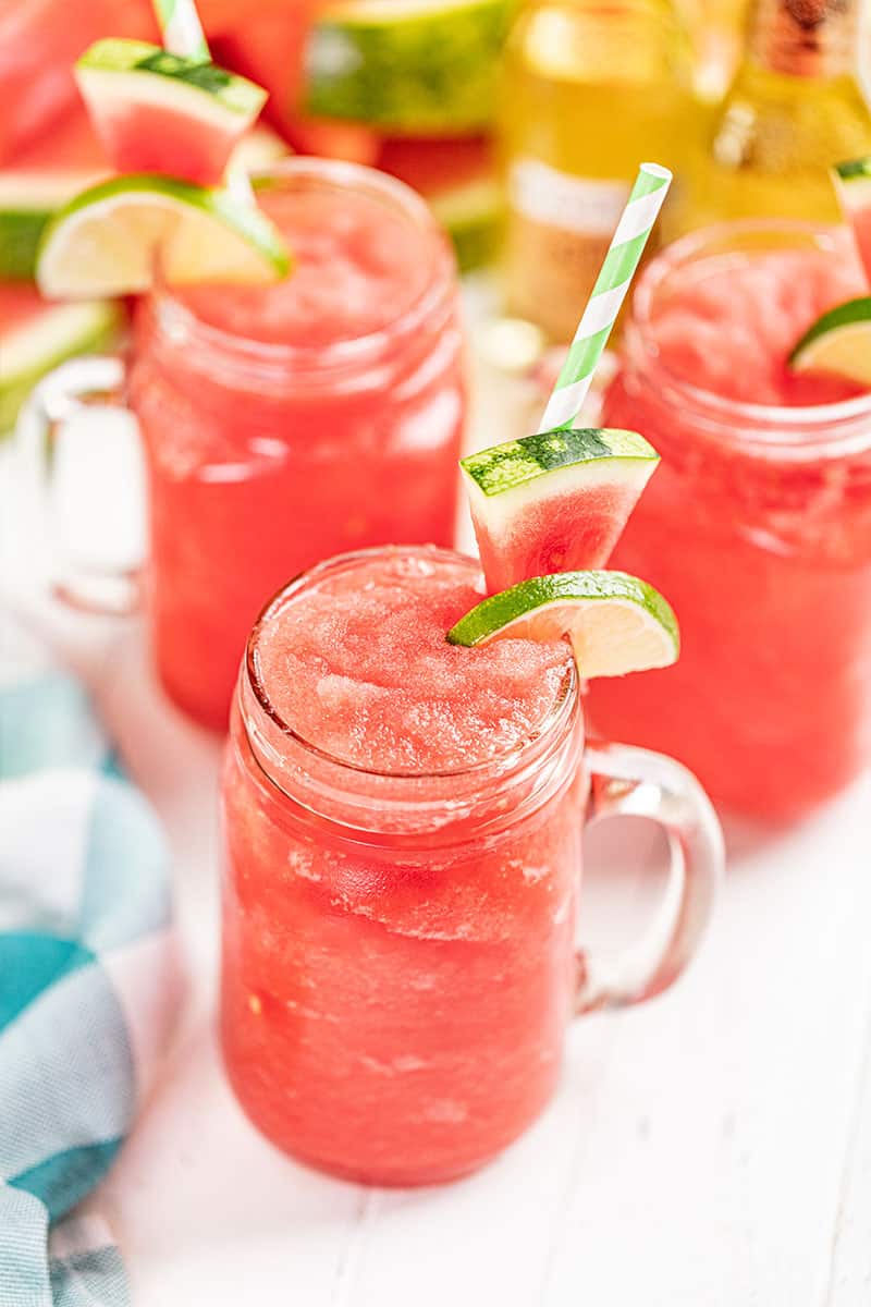 Watermelon slushies in drinking glasses with paper straws.