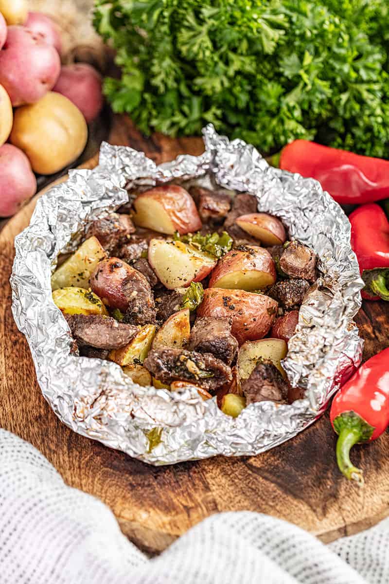 Steak and potatoes in an open foil packet.