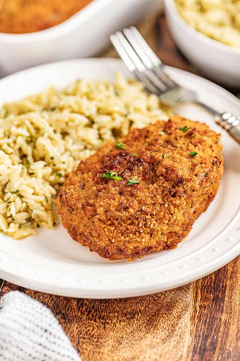 A crispy breaded pork chop on a dinner plate.