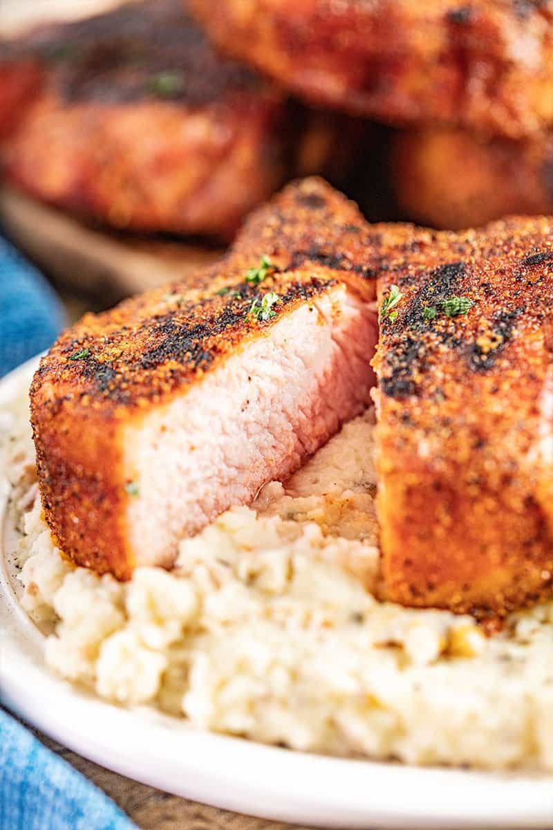 Smoked pork chop cut in half on top of mashed potatoes.