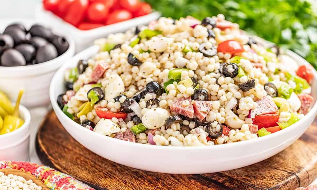 Italian couscous salad in a large white serving bowl.