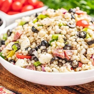 Italian couscous salad in a large white serving bowl.