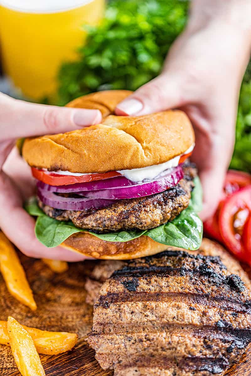 Two hands holding a large turkey burger.