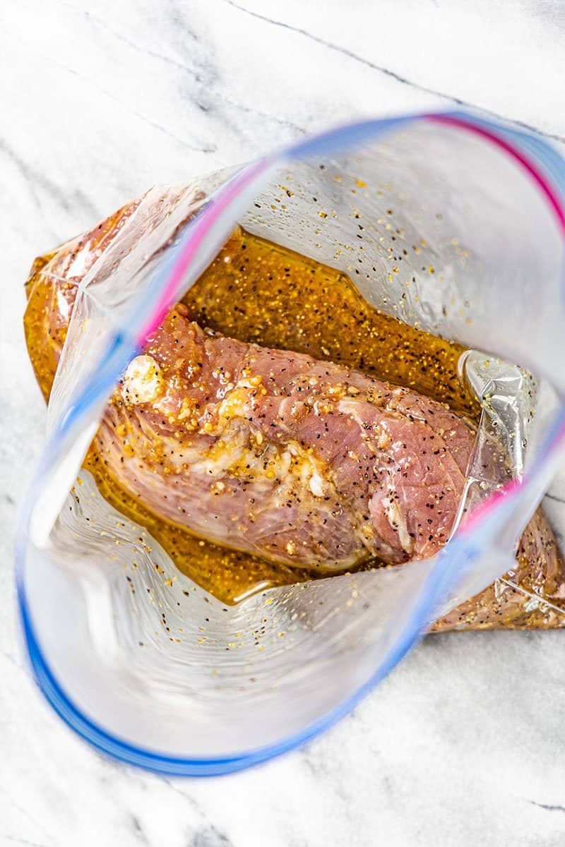 Overhead view of a pork tenderloin marinating in a plastic bag.