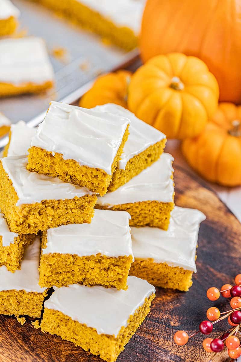 A stack of pumpkin bars on a wooden serving tray.