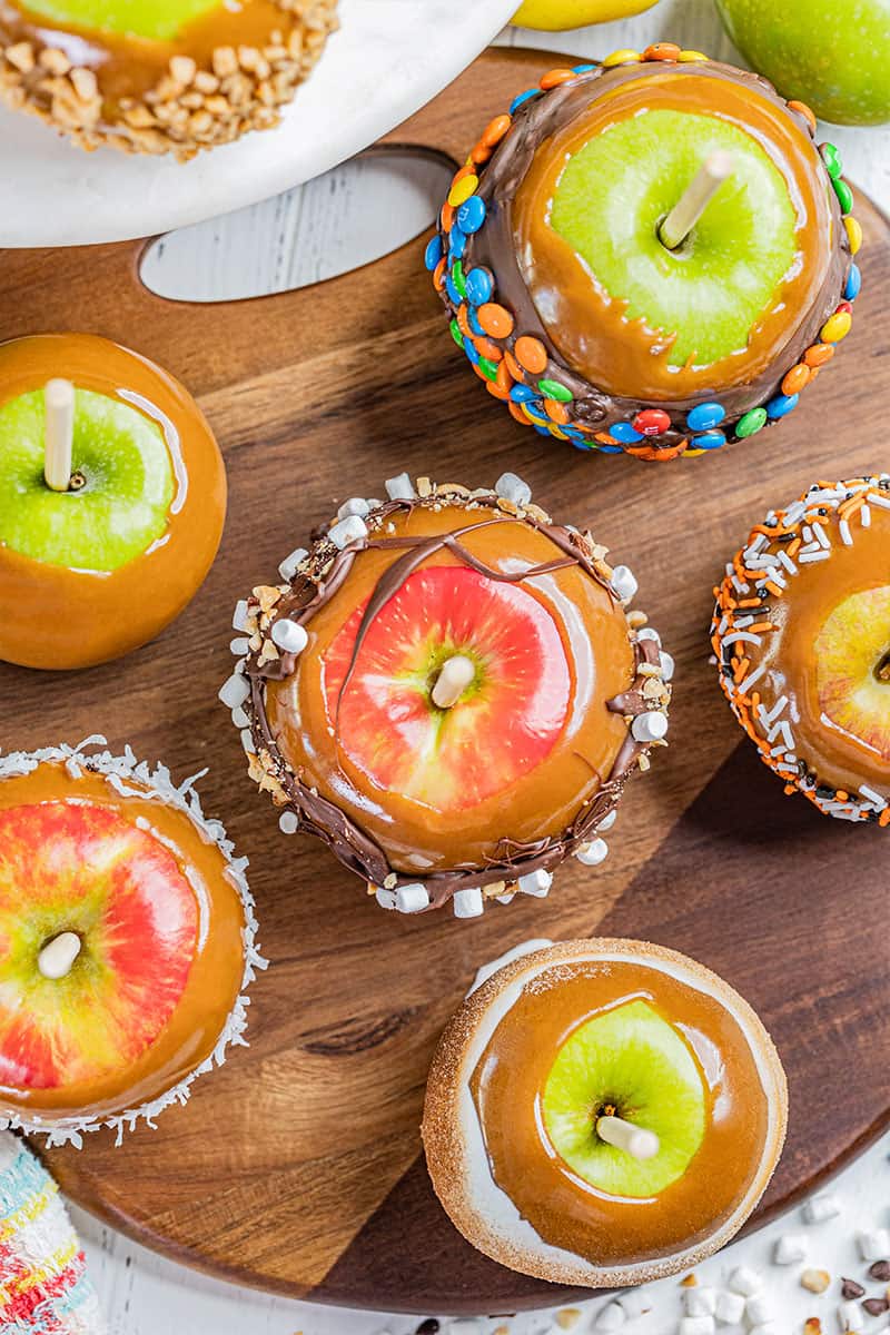 Overhead view of homemade caramel apples with various toppings.