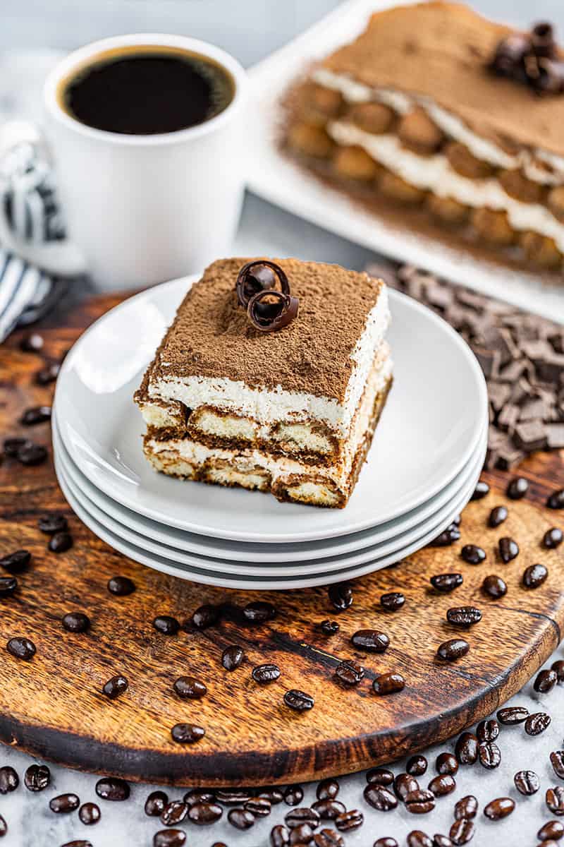 A slice of tiramisu on a plate with a mug of coffee.