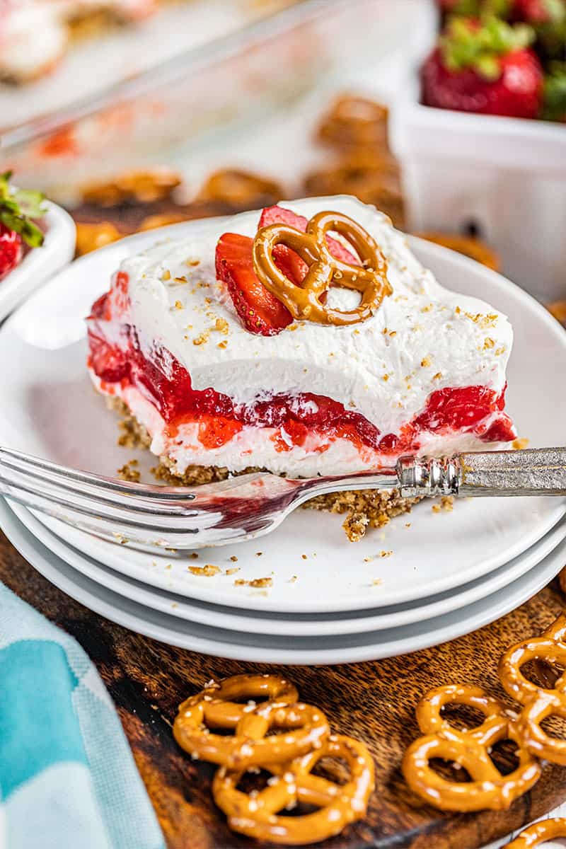 A slice of strawberry pretzel salad with a bite removed.
