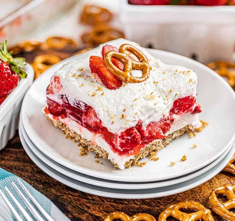 A slice of strawberry pretzel salad on a stack of plates.