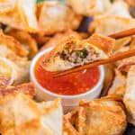 Chopsticks holding a sausage wonton.