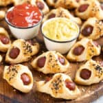 Pigs in a blanket on a wood serving tray.
