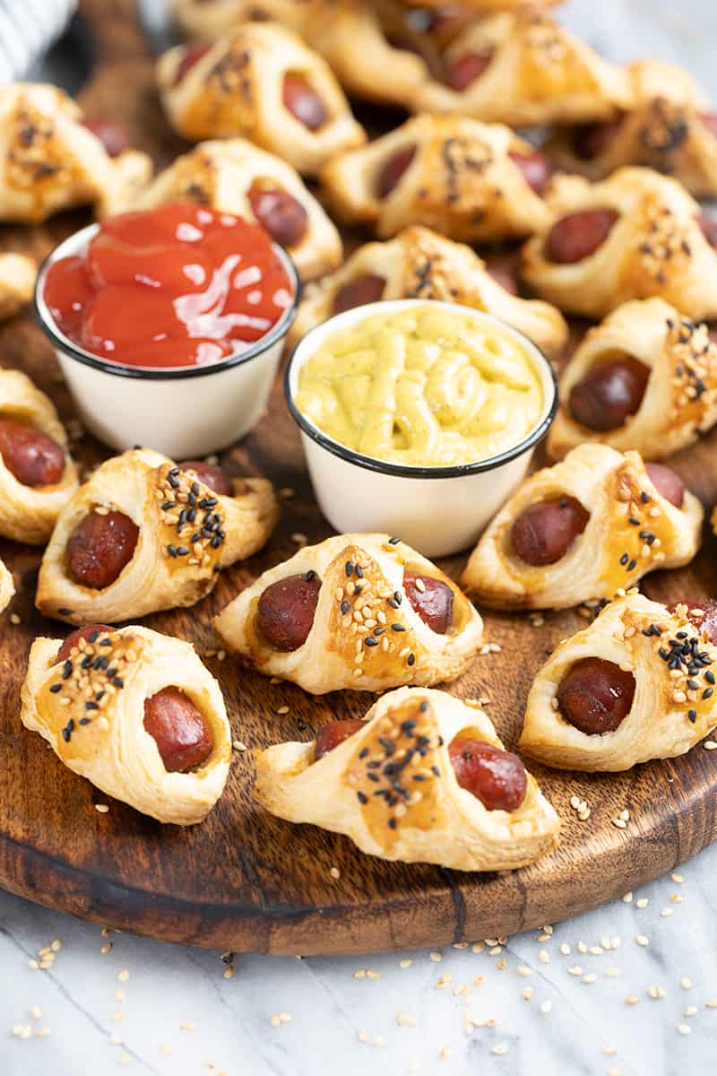 Pigs in a blanket on a wood serving tray.