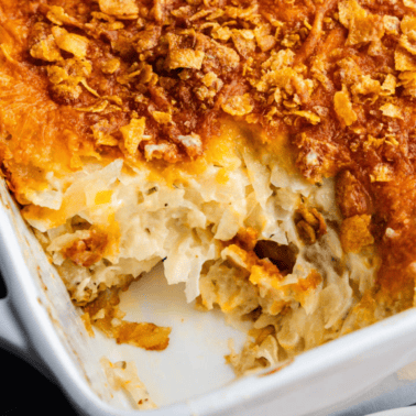 A casserole pan of funeral potatoes with a scoop taken out.